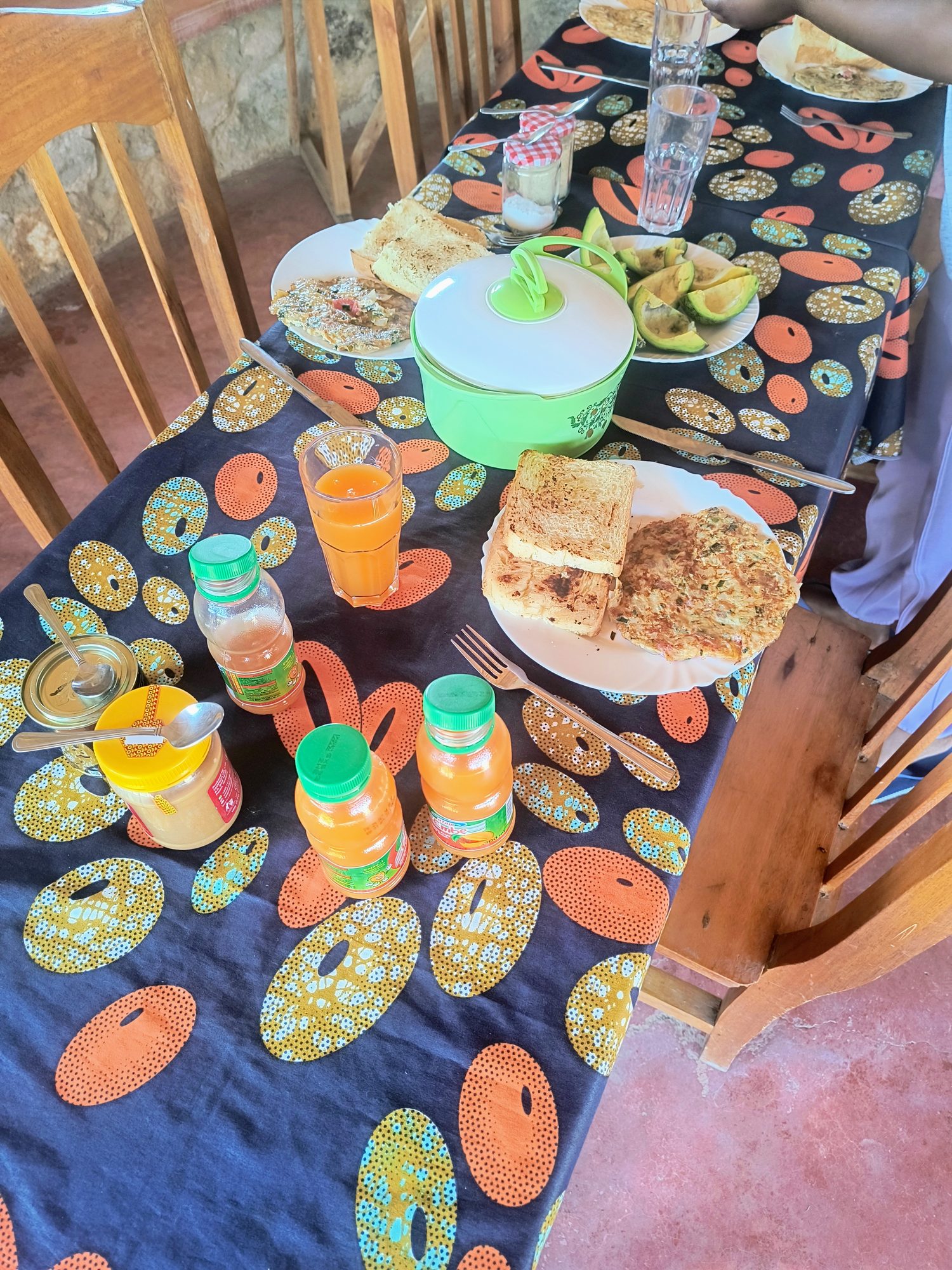 Breakfast table laid with colourful kitenge cloth, juice and fresh food at MARK's Farm & Lodge
