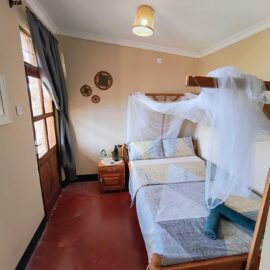 Double room with a bed under a mosquito net and a bedside table with warm light